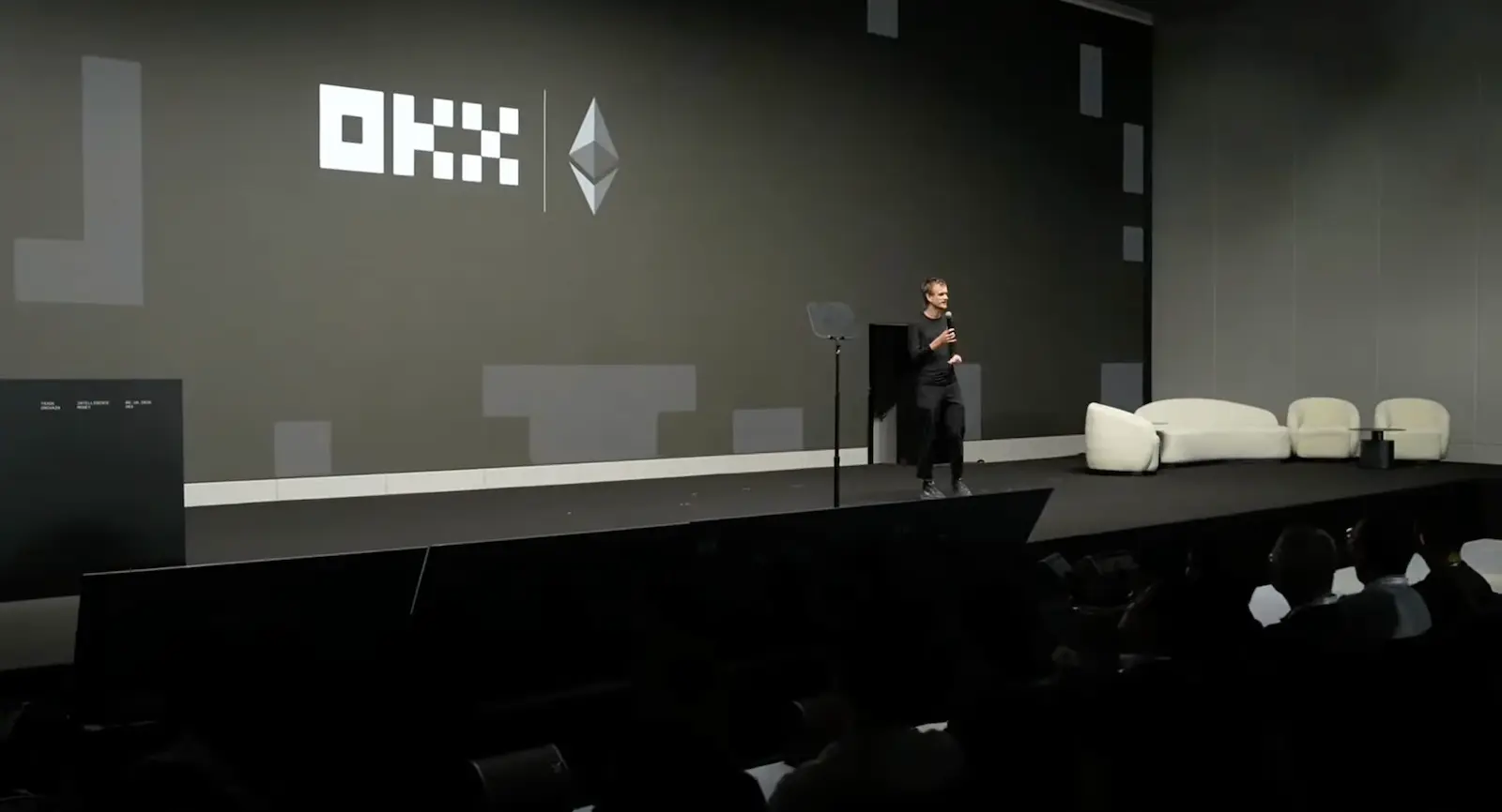 Vitalik Buterin auf der Bühne des OKX-NOW-Events in Singapur, mit den Logos von OKX und Ethereum im Hintergrund.